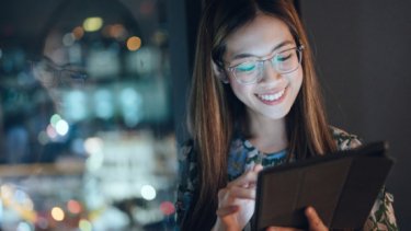 A smiling girl  with eyeglasses and a laptop